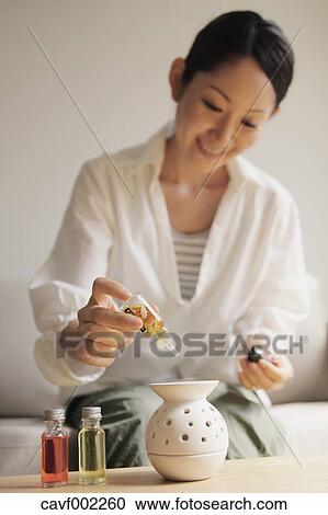 Stock Image - Woman pouring essence oil in a pot. Fotosearch