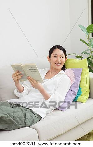 Stock Image - Woman reading a book on the sofa. Fotosearch