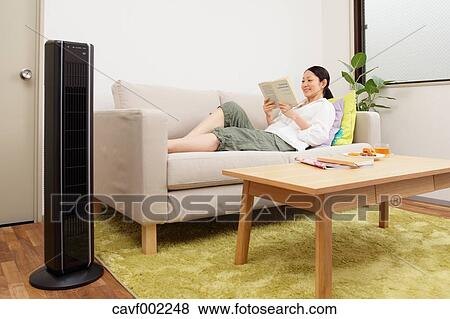 Stock Photo - Woman reading a book on the sofa. Fotosearch