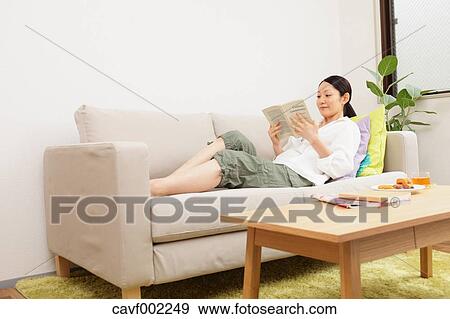 Stock Photo - Woman reading a book on the sofa. Fotosearch