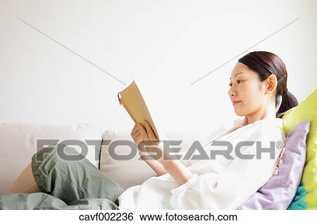 Woman reading a book on the sofa View Large Photo Image Stock Photograph - Woman reading a book on the sofa. Fotosearch