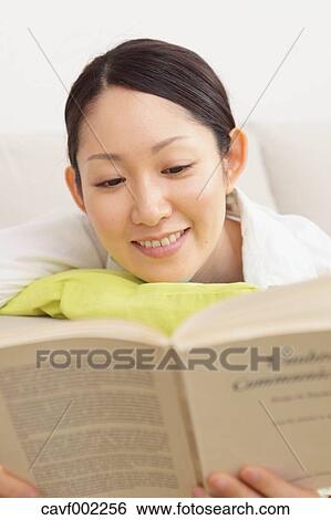 Stock Photograph - Woman reading a book on the sofa. Fotosearch