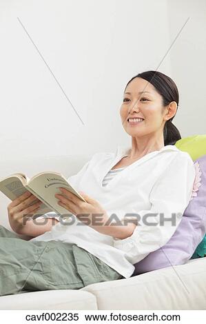 Woman reading a book on the sofa View Large Photo Image Stock Photography - Woman reading a book on the sofa. Fotosearch