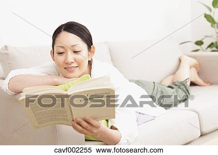Stock Photography - Woman reading a book on the sofa. Fotosearch