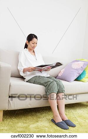 Woman reading a magazine on the sofa View Large Photo Image Stock Image - Woman reading a magazine on the sofa. Fotosearch