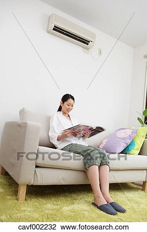 Woman reading a magazine on the sofa View Large Photo Image Stock Image - Woman reading a magazine on the sofa. Fotosearch