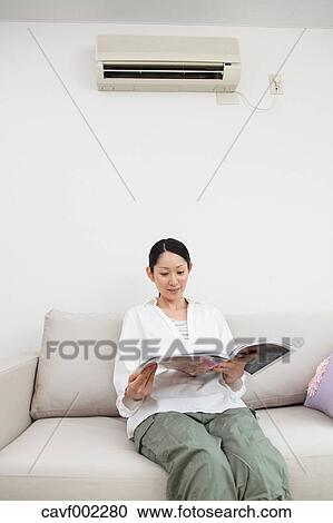 Woman reading a magazine on the sofa View Large Photo Image Stock Image - Woman reading a magazine on the sofa. Fotosearch