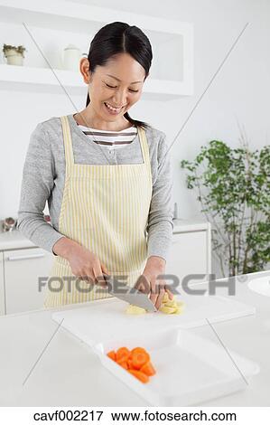 Woman slicing vegetables in an open kitchen View Large Photo Image Stock Photo - Woman slicing vegetables in an open kitchen. Fotosearch