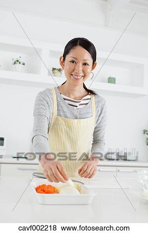 Woman slicing vegetables in an open kitchen View Large Photo Image Stock Photo - Woman slicing vegetables in an open kitchen. Fotosearch