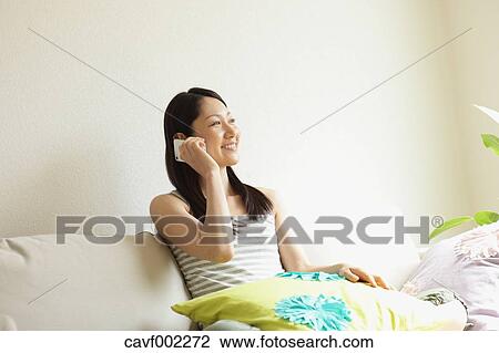 Stock Image - Woman talking on the phone on the sofa. Fotosearch