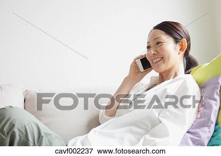 Stock Photo - Woman talking on the phone on the sofa. Fotosearch