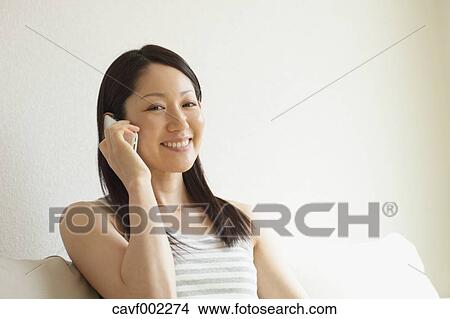 Picture - Woman using a Smartphone on the sofa. Fotosearch