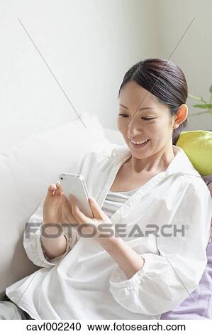 Woman using a Smartphone on the sofa View Large Photo Image Stock Image - Woman using a Smartphone on the sofa. Fotosearch