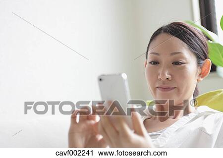 Stock Image - Woman using a Smartphone on the sofa. Fotosearch