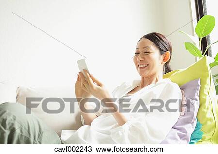 Stock Image - Woman using a Smartphone on the sofa. Fotosearch