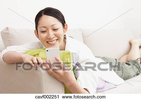 Woman using a Smartphone on the sofa View Large Photo Image Stock Image - Woman using a Smartphone on the sofa. Fotosearch