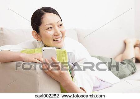 Stock Image - Woman using a Smartphone on the sofa. Fotosearch