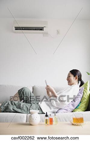 Stock Image - Woman using a Smartphone on the sofa. Fotosearch