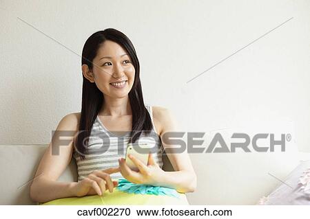 Woman using a Smartphone on the sofa View Large Photo Image Stock Image - Woman using a Smartphone on the sofa. Fotosearch