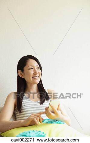 Woman using a Smartphone on the sofa View Large Photo Image Stock Image - Woman using a Smartphone on the sofa. Fotosearch