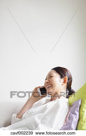 Stock Photo - Woman using a Smartphone on the sofa. Fotosearch