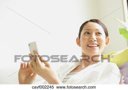Woman using a Smartphone on the sofa View Large Photo Image Stock Photography - Woman using a Smartphone on the sofa. Fotosearch