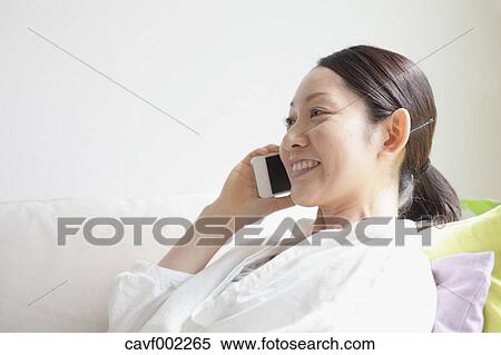 Stock Photography - Woman using a Smartphone on the sofa. Fotosearch