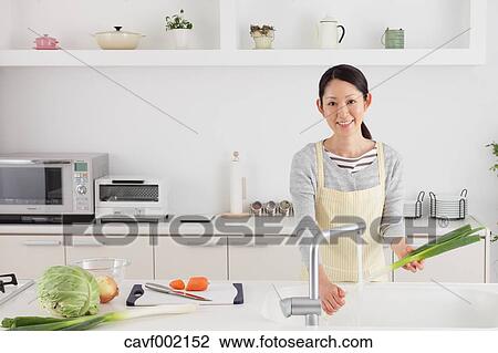 Woman washing green onions in an open kitchen View Large Photo Image Stock Image - Woman washing green onions in an open kitchen. Fotosearch