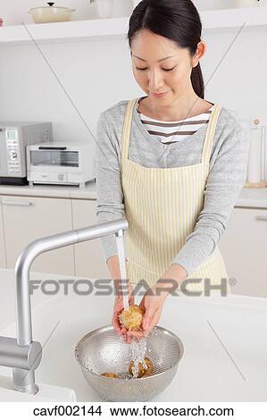 Picture - Woman washing potatoes. Fotosearch