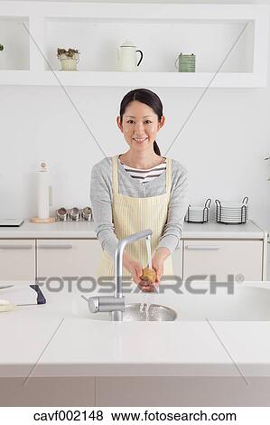 Stock Photo - Woman washing potatoes. Fotosearch