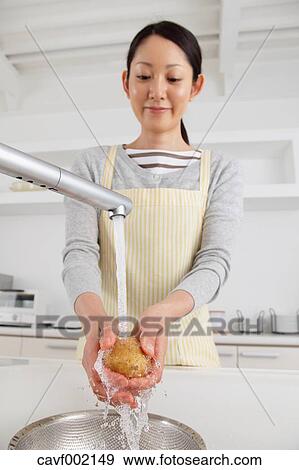 Stock Photo - Woman washing potatoes. Fotosearch