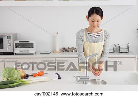 Stock Photograph - Woman washing potatoes. Fotosearch