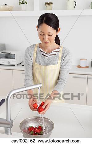 Stock Image - Woman washing strawberries. Fotosearch