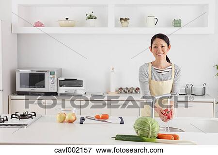 Woman washing tomatoes in an open kitchen View Large Photo Image Stock Photo - Woman washing tomatoes in an open kitchen. Fotosearch