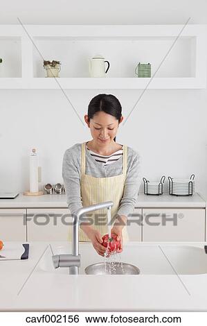 Woman washing tomatoes in an open kitchen View Large Photo Image Stock Photograph - Woman washing tomatoes in an open kitchen. Fotosearch