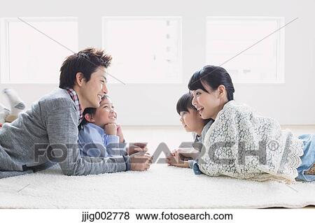 Young adult couple and their children laying on the floor and smiling at each other View Large Photo Image Stock Photo - Young adult couple and their children laying on the floor and smiling at each other. Fotosearch