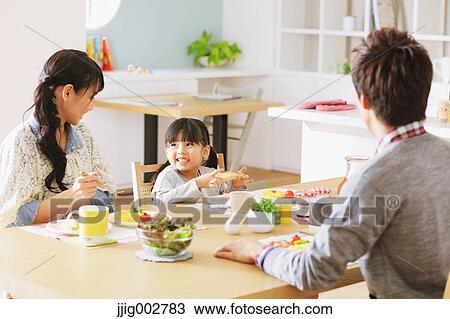 Stock Image - Young adult couple and their daughter having breakfast in their dining room. Fotosearch
