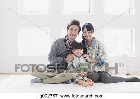 Young adult couple and their daughter sitting on the floor and smiling at camera View Large Photo Image Stock Photo - Young adult couple and their daughter sitting on the floor and smiling at camera. Fotosearch