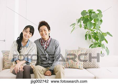 Stock Image - Young adult couple relaxing on the sofa. Fotosearch