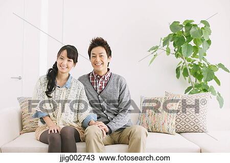 Stock Image - Young adult couple relaxing on the sofa. Fotosearch