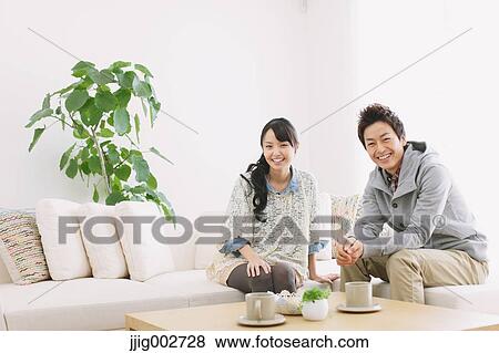 Young adult couple relaxing on the sofa and smiling at camera View Large Photo Image Stock Photo - Young adult couple relaxing on the sofa and smiling at camera. Fotosearch