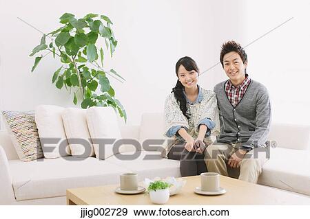 Stock Photo - Young adult couple relaxing on the sofa. Fotosearch