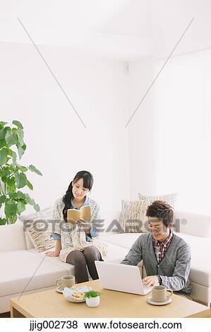 Stock Photo - Young adult couple relaxing on the sofa. Fotosearch