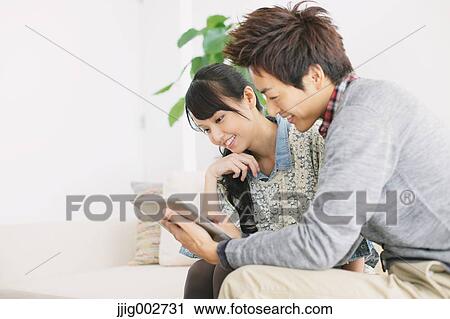 Young adult couple relaxing with tablet on the sofa View Large Photo Image Stock Image - Young adult couple relaxing with tablet on the sofa. Fotosearch
