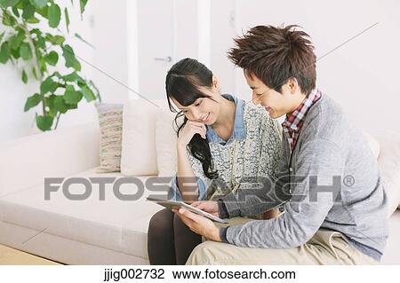 Young adult couple relaxing with tablet on the sofa View Large Photo Image Stock Image - Young adult couple relaxing with tablet on the sofa. Fotosearch