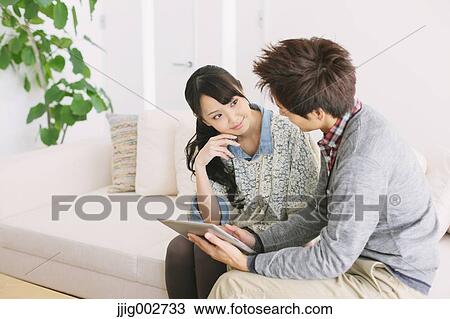 Young adult couple relaxing with tablet on the sofa View Large Photo Image Stock Image - Young adult couple relaxing with tablet on the sofa. Fotosearch