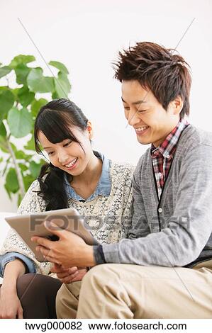 Young adult couple relaxing with tablet on the sofa View Large Photo Image Stock Image - Young adult couple relaxing with tablet on the sofa. Fotosearch