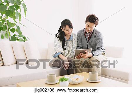 Young adult couple relaxing with tablet on the sofa View Large Photo Image Stock Photograph - Young adult couple relaxing with tablet on the sofa. Fotosearch