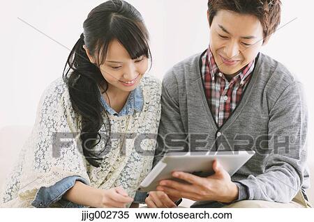 Young adult couple relaxing with tablet on the sofa View Large Photo Image Stock Photography - Young adult couple relaxing with tablet on the sofa. Fotosearch