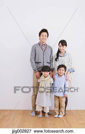 Young adult couple with their kids standing in front of a white wall and smiling at camera View Large Photo Image Stock Photo - Young adult couple with their kids standing in front of a white wall and smiling at camera. Fotosearch